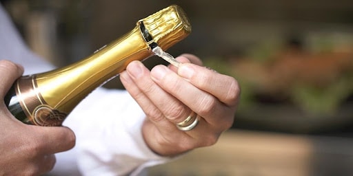 Male-hands-uncorking-a-bottle-of-champagne-wine