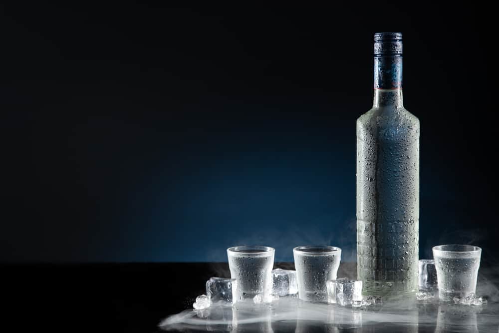 Ice-cold bottle of Vodka with shot glasses; one of the home bar essential liquors