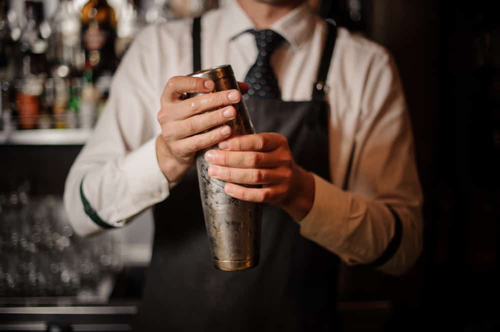 Professional-male-bartender-holding-steel-shaker-in-a-bar.